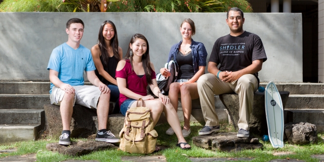 Undergraduate students sit on steps in the Shidler courtyard.